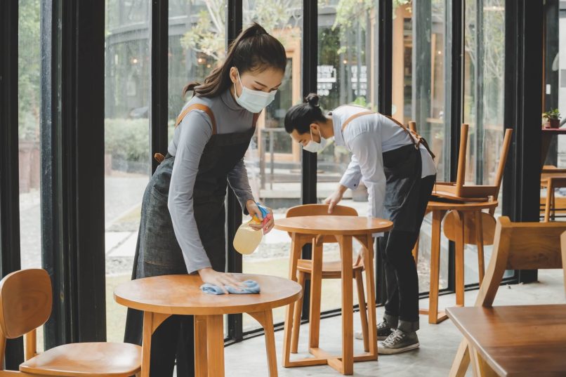 Waiter & Waitress Cleaning Tables To Stop Spread Of COVID-19