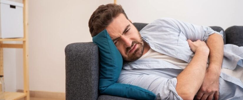 Sick Man On Couch Wondering How Long Does Food Poisoning Last