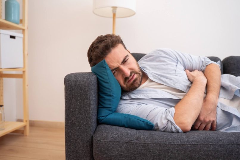 Sick Man On Couch Wondering How Long Does Food Poisoning Last